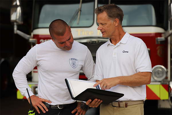 Erik Swanson going over documents in a binder in front of a firetruck outside of the firestation