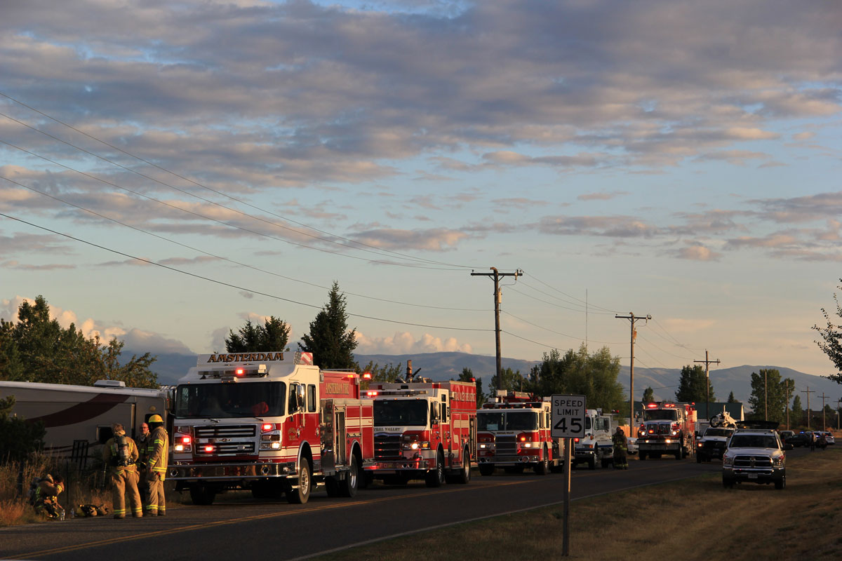 Firetrucks parked along a street with mountains in the distance