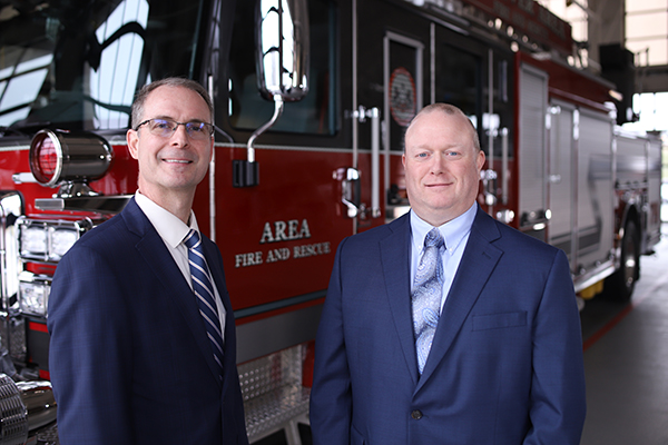 Peter Feid and Mark Harrington standing in front of a firetruck