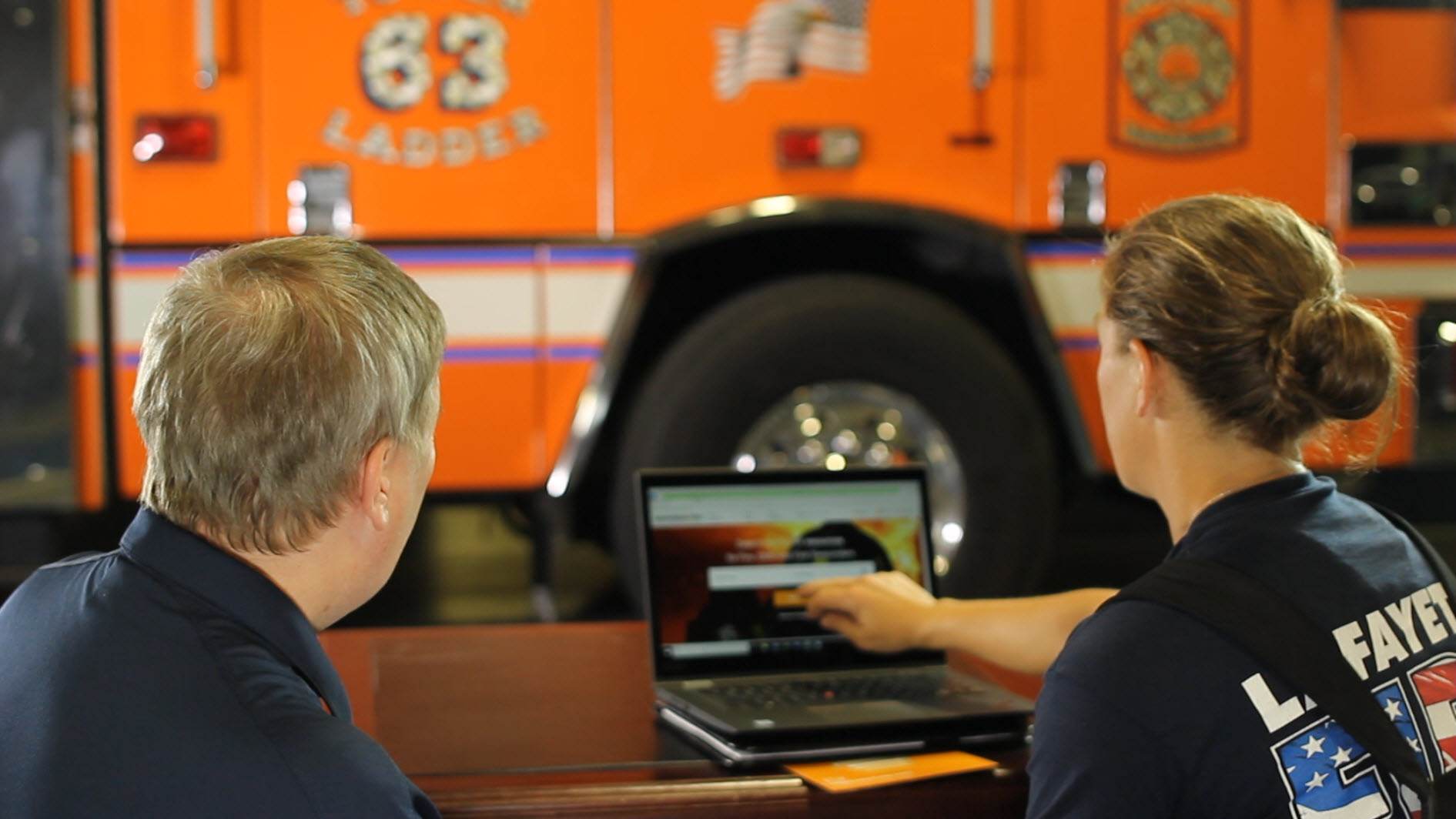 Two firefighters using ResponderHelp on a laptop in the station