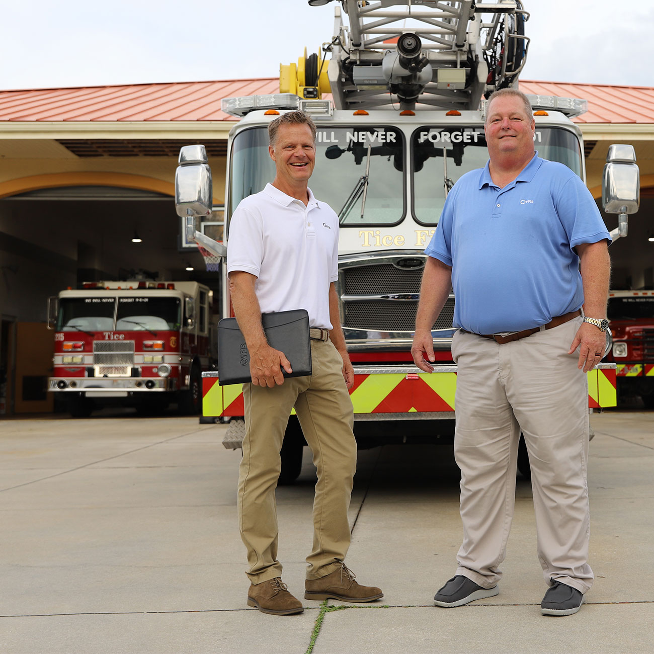 Eric and Russ, VFIS Associates, posing in front of a Firetruck at the Tice Fire Station.