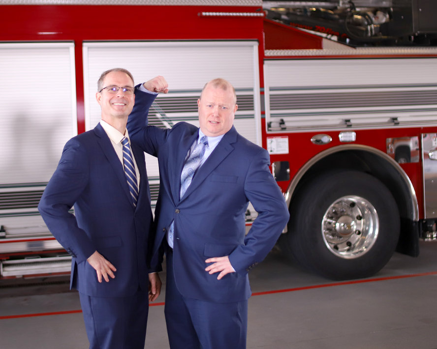 Peter and Mark smiling in front of a firetruck