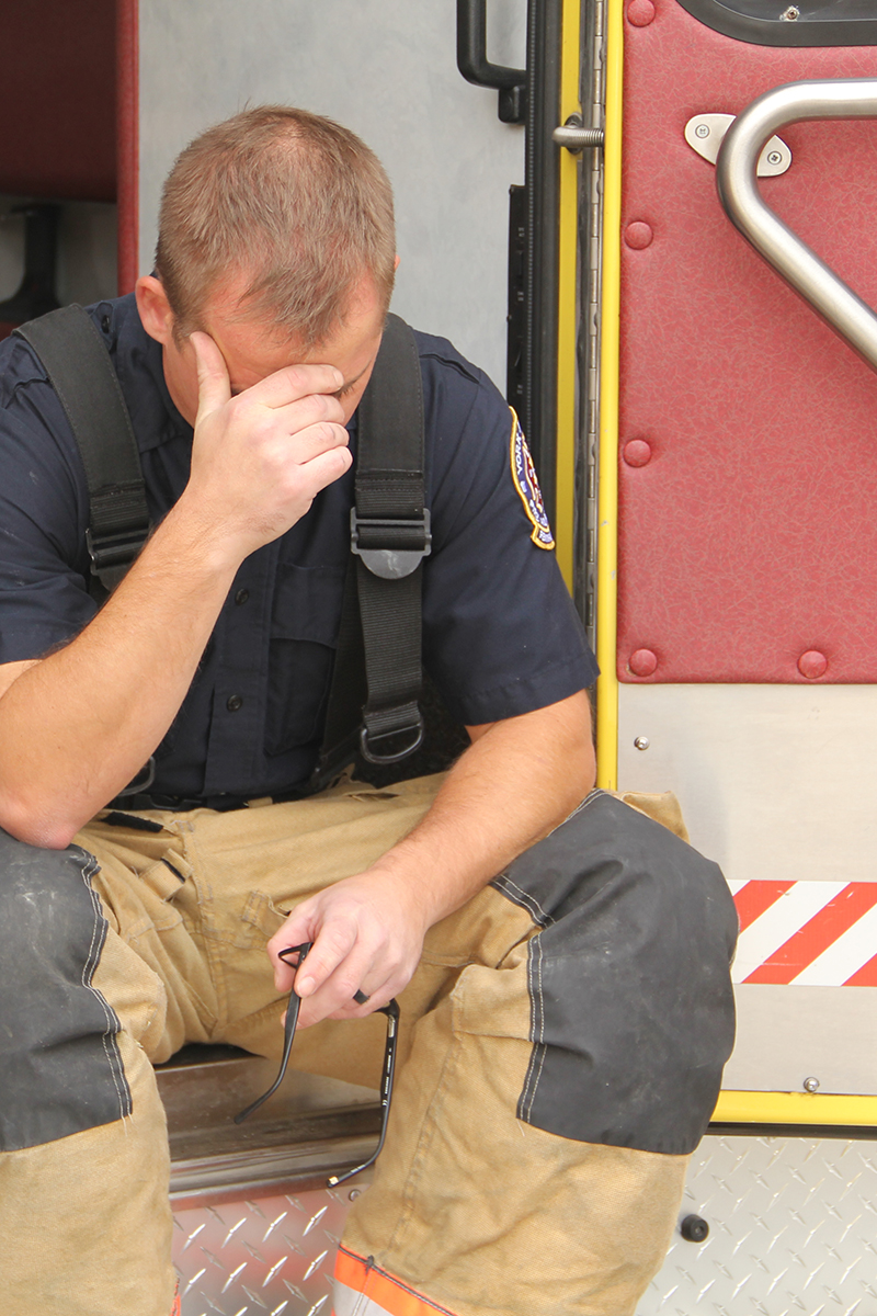 A firefighter hanging his head down into his hands